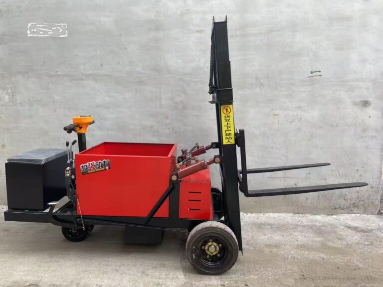Red electric forklift with extended forks and lifting mast, photographed at the manufacturer