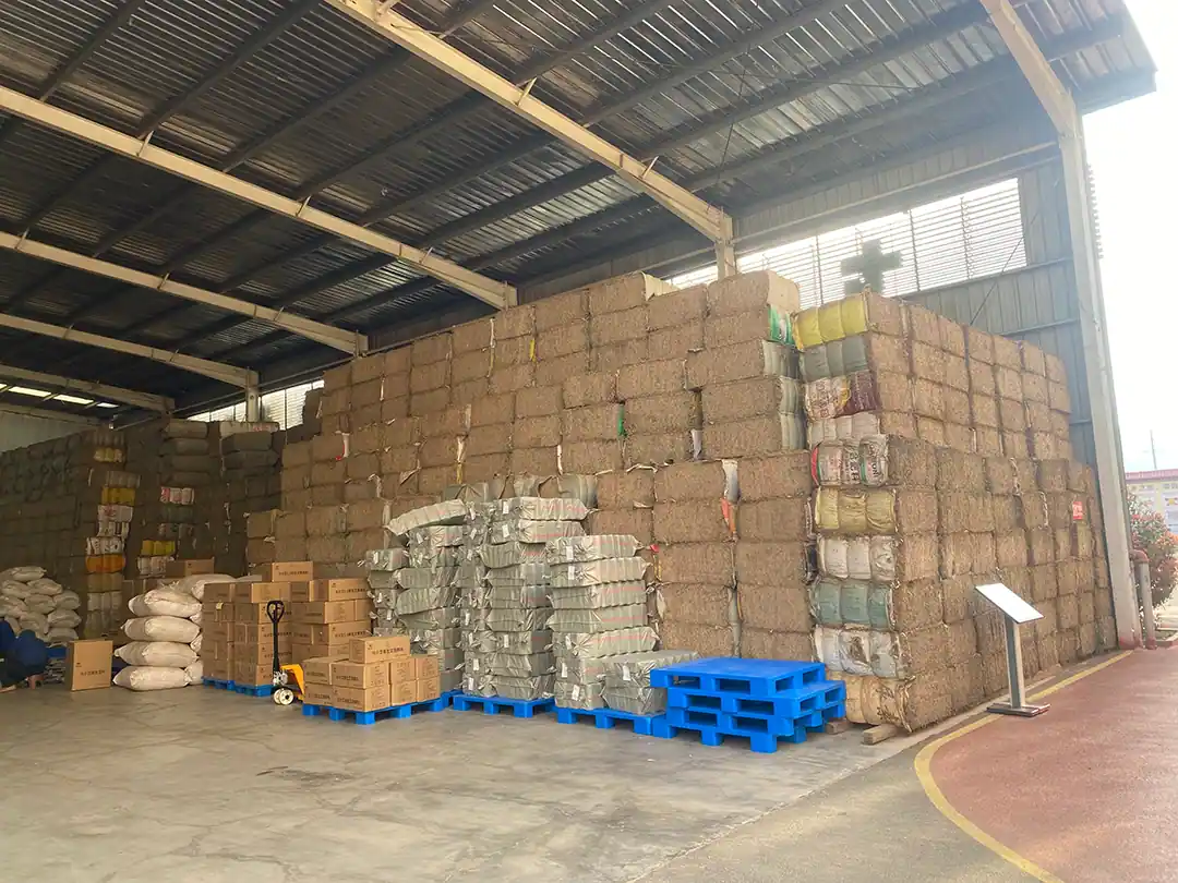 Factory warehouse with stacked material bales, cartons and pallets