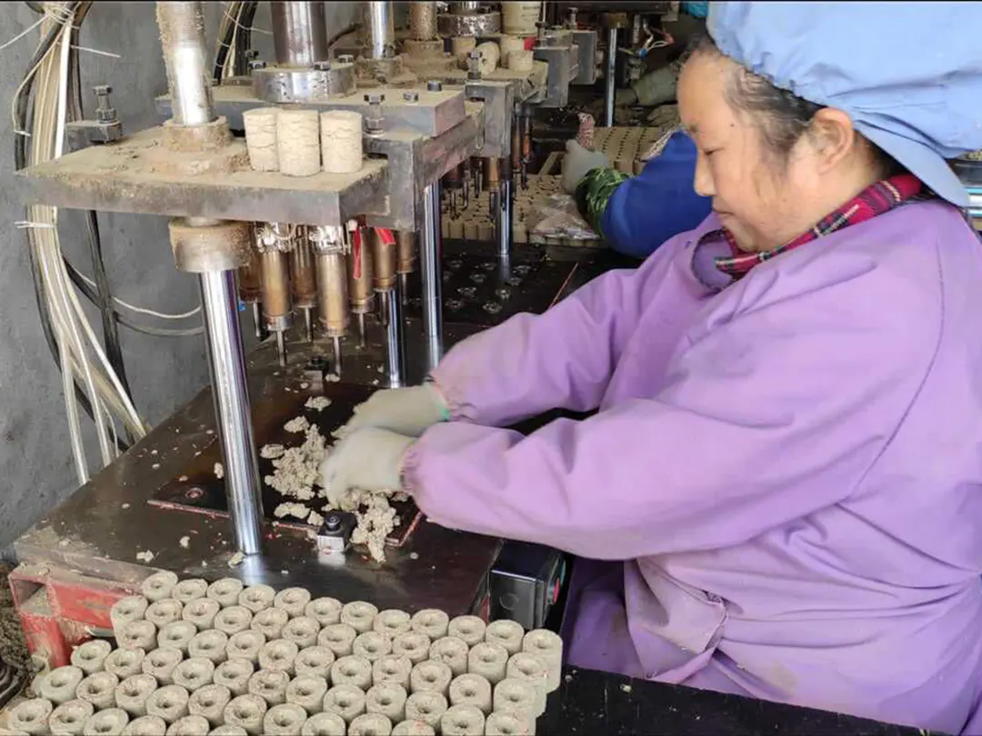 Worker operating equipment at a moxa-product forming workstation