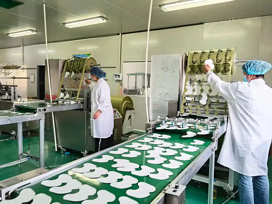Workers handling sheet materials on a factory cutting and conveyor line